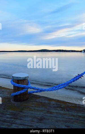 In prossimità di una corda blu l'ormeggio di una nave in un coperto di ghiaccio baia del porto. Foto Stock