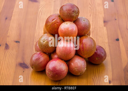 Più bel rosso passione Frutta (Passiflora edulis) presentate spennate e impilate una sull'altra su di un tavolo di legno. Foto Stock