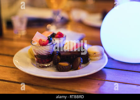 Piastra in ceramica con assortimento di deliziosi dessert collocato sul tavolo di legno in ristorante a Dubai Foto Stock