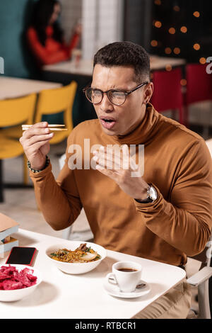 Il cliente sorpreso perché ordinati pasto in ristorante Asiatico molto piccante. Foto Stock