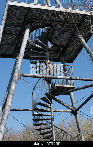 Donna adulta clinbing giù per le scale di una torre di avvistamento di metallo nel slikken van heen dutch national park Foto Stock