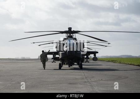 Un U.S. Massa dell'esercito membro di equipaggio del primo combattimento Brigata Aerea, 1a Divisione di Fanteria dà un pollice su per l'equipaggio di un AH-64 elicottero Apache, pronto a lasciare Wingene Air Base, Belgio, Febbraio 7, 2019. Wingene Air Base è servita come un intermedio area di sosta prima della 1a combattere la Brigata Aerea distribuisce in Germania, Polonia, Lettonia e Romania per nove mesi al treno con i partner della NATO a sostegno della Atlantic risolvere. Foto Stock