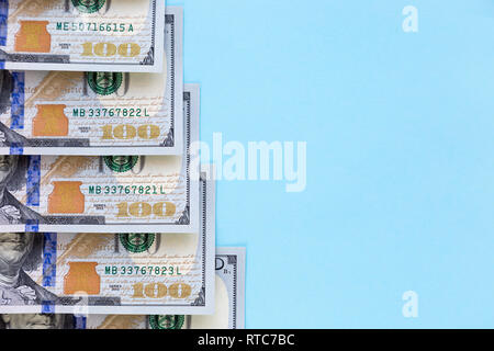 Hundred Dollar Bills giacciono sotto forma di una scala su uno sfondo blu con spazio libero per il testo Foto Stock