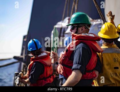 Mare Mediterraneo (feb. 10, 2019) Yeoman marinaio Patrick Jones del Cantone, Ohio segnali per Henry Kaiser-class flotta oliatore di rifornimento USNS John Lenthall (T-AO 188) a bordo di San Antonio-classe di trasporto anfibio dock nave USS Arlington (LPD 24) durante un rifornimento in mare, il 10 febbraio, 2019. Arlington è su una distribuzione programmata come parte dell'anfibio Kearsarge Gruppo pronto a sostegno della sicurezza marittima, operazioni di risposta alle crisi del teatro e la cooperazione in materia di sicurezza, fornendo nel contempo anche un avanzamento presenza navale. Foto Stock