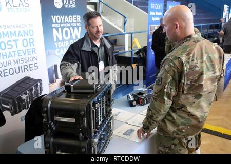 Stati Uniti Comando Esercito Sgt. Il Mag. Michael Conaty, il 2d teatro vigili del segnale senior leader arruolato, parla con Gerhard Schultz, un fornitore con Klas Telecom, a Wiesbaden Tech Expo, 14 febbraio, 2019, di Wiesbaden, Germania. Foto Stock