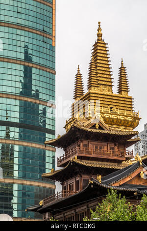 Il Jing' un tempio o tempio di pace e tranquillità con la sua vistosamente decorata e dorata torre sorge giustapposti con il grattacielo dietro. Foto Stock