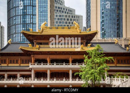 Un doppio tradizionale gronda del tetto ornato di Jing' un tempio o tempio di pace e di tranquillità giustapposti con le sue linee eleganti di grattacieli dietro. Foto Stock