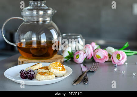 Una sana colazione a base di frittelle di ricotta con frutti di bosco e tè verde in un bicchiere tè pentola. Copia dello spazio. La dieta dolce concetto. Foto Stock