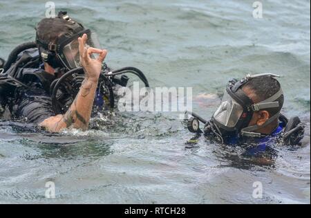 SANTA RITA, Guam (feb. 19, 2019) Navy Diver 2a classe Alec Stuller, a sinistra un subacqueo di sicurezza assegnato al mobile di immersioni subacquee e di unità di soccorso (MDSU) 1, fornisce il segnale di OK dopo aver eseguito i controlli di sicurezza di un dello Sri Lanka subacqueo della marina militare durante il corso di formazione in preparazione per esercitare la cooperazione a galla la prontezza e la formazione (Carati) Sri Lanka 19. Questo pre-allenamento è stato progettato per familiarizzare il di Sri Lanka team con attrezzature e pratiche che portano fino a caso a partire da aprile. Foto Stock