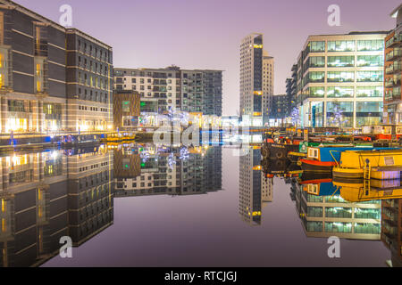 Le riflessioni di ormeggiati narrowboats e appartamenti a Leeds Dock Foto Stock