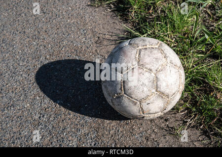 Bianco invecchiato pallone da calcio su strada asfaltata Foto Stock