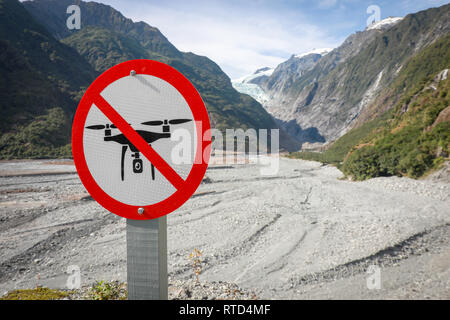 Segno accanto al percorso trail al ghiacciaio Franz Josef dicendo no fuchi con ghiaia riverbed e il ghiacciaio in backgroundNew Zelanda Isola del Sud Foto Stock