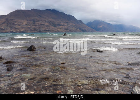 Basso livello immagine di piccole onde sul lago Wakatipu con Cecil picco in background su un nuvoloso giorno ventoso, Queenstown, New Zealand Nuova Zelanda Isola del Sud Foto Stock