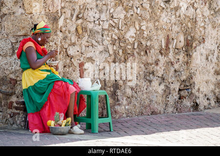 Cartagena Colombia,Black Afro Caribbean Palenquera,venditore di frutta,donna donna donne,mangiare,seduta,costume tradizionale,simbolo del patrimonio culturale,COL1901 Foto Stock