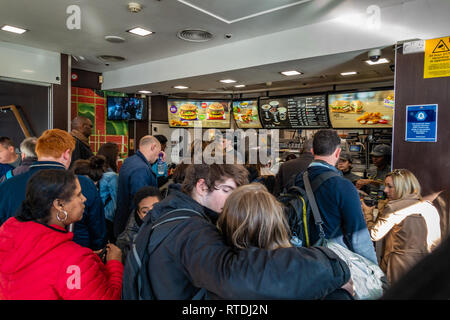 Coda di grandi dimensioni di persone in attesa di essere serviti a McDonalds, Kings Cross a Londra, Inghilterra Foto Stock