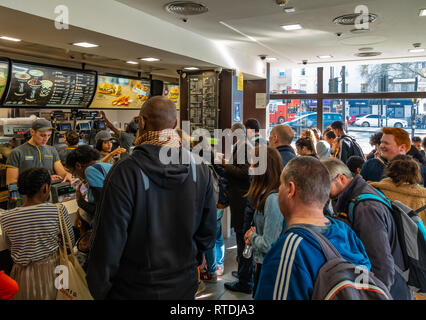 Coda di grandi dimensioni di persone in attesa di essere serviti a McDonalds, Kings Cross a Londra, Inghilterra Foto Stock