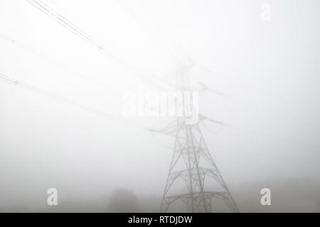 Basso angolo di vista pilone di elettricità in early MORNING MIST Foto Stock