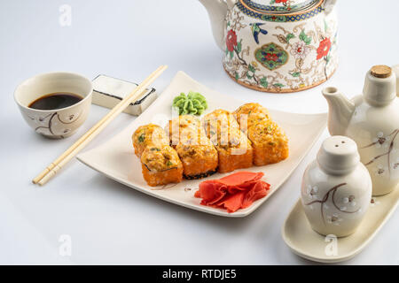 Sfornati con smerlo tar-tar, salsa piccante, crema di formaggio e mango con riso su piastra bianca con bordo dorato. Menu asiatici Foto Stock