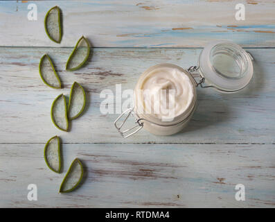 In casa la Crema di Aloe vera in un vasetto di vetro, con taglio Aloe foglie su un leggero sottofondo in legno Foto Stock