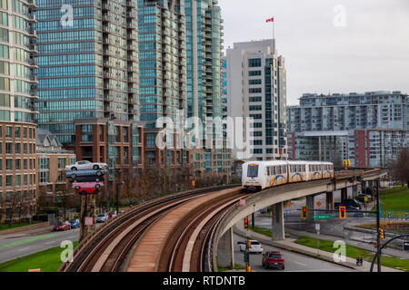 Il centro di Vancouver, British Columbia, Canada - 29 Novembre 2018: lo Skytrain che passa nella città moderna durante una sera Nuvoloso. Foto Stock