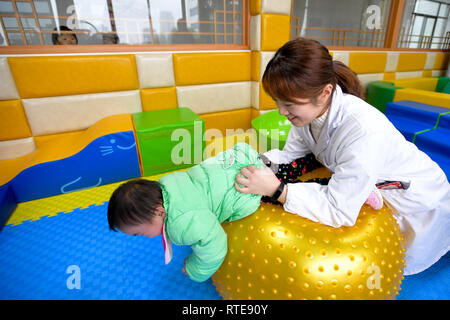 (190301) -- CHANGSHA, 1 marzo 2019 (Xinhua) -- terapista della riabilitazione Yang Yan (R) aiuta un 2-year-old orphan diagnosticato con paralisi cerebrale effettuare la riabilitazione di formazione presso il primo ospedale di Hunan Università di Medicina cinese di Changsha, capitale della centrale provincia cinese di Hunan, 1 marzo 2019. Un totale di 18 orfani con disabilità sono state trattate nel primo ospedale di Hunan Università di Medicina Cinese di venerdì sotto il "Piano di domani", un Progetto nazionale finanziato dal Ministero per gli affari civili che iniziò nel 2004, che mira ad offrire gratuitamente le cure mediche per disabili orpha Foto Stock