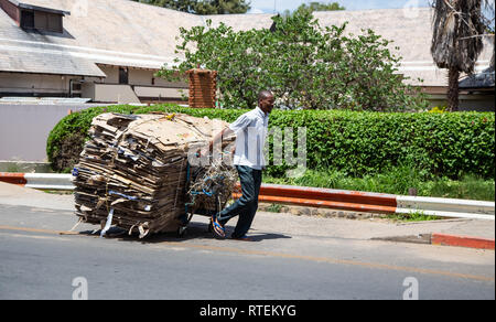 Francistown, Botswana, 7 gennaio - 2019: Rifiuti picker tirando lungo il carrello riempito con cartone riciclabile. Foto Stock