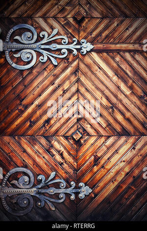 Dettaglio su una vecchia porta di legno con cerniere metalliche Foto Stock