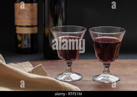 Due bicchieri di vino rosso sul tavolo di legno, sfondo scuro, closeup vista frontale Foto Stock