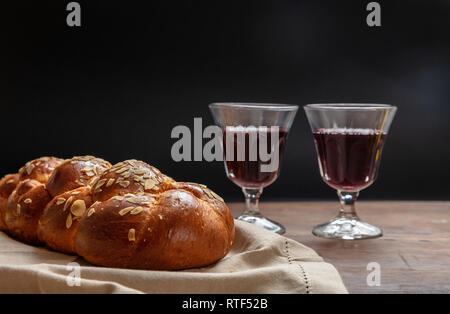 Concetto di Shabbat, challah pane con due bicchieri di vino rosso sul tavolo di legno Foto Stock