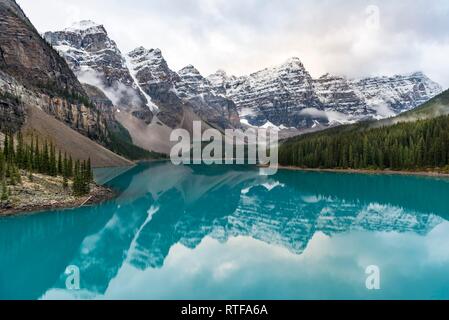 Nuvole e sospesi tra picchi di montagna e la riflessione in turchese lago glaciale, Moraine Lake, Valle dei Dieci Picchi Foto Stock