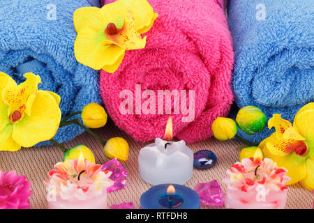 Spa con asciugamani, candele e fiori su sfondo di bambù. Foto Stock