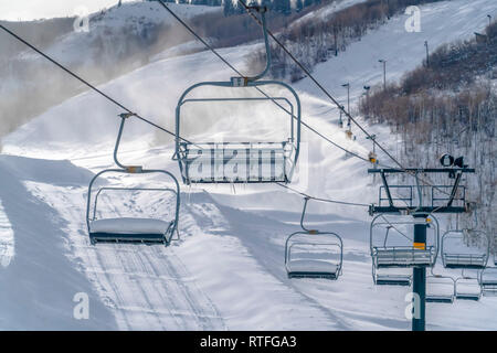 Impianti di risalita sulla montagna innevata e cannoni da neve. Impianti di risalita sulla montagna innevata con cannoni da neve su una stazione sciistica in Park City, Utah. Sunligh luminoso Foto Stock