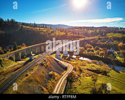 Vecchio viadotto ferroviario in montagna. In autunno il paesaggio rurale con il viadotto ferroviario, villaggio Vorohta nella gamma dei Carpazi. Transcarpathia Foto Stock