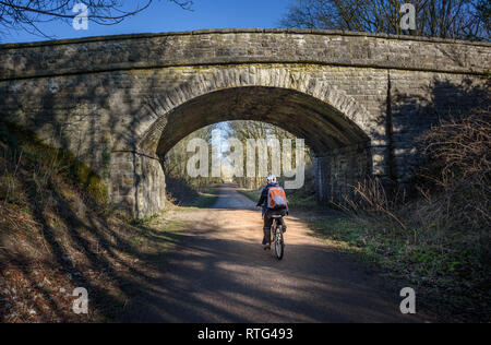 Un ciclista passando sotto uno dei viadotti ferroviari su teh Monsal Trail, Derbyshire, Peak District, UK. Foto Stock