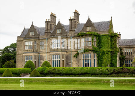 Muckross House e giardini contro il cielo nuvoloso. Si tratta di un palazzo progettato in stile Tudor, situato nel Parco Nazionale di Killarney. Foto Stock