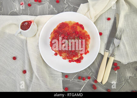 American pancake con la marmellata - berry, pallon di maggio, mirtillo rosso su sfondo grigio. Pancake fatti in casa con salsa di frutti di bosco e le foglie di menta. Sana colazione con prodotti freschi h Foto Stock