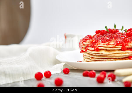 American pancake con la marmellata - berry, pallon di maggio, mirtillo rosso su sfondo grigio. Pancake fatti in casa con salsa di frutti di bosco e le foglie di menta. Sana colazione con prodotti freschi h Foto Stock