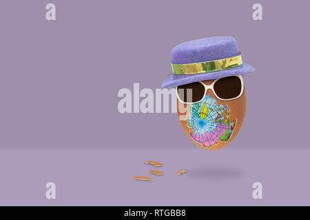L'uovo sgusciato ha un globo interno con gli occhiali e il cappello è volare su sfondo viola. Concetto di pasqua. Foto Stock