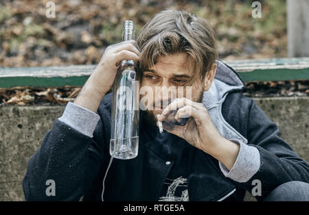Close up man mano un bicchiere di vodka. Bevuto giovani. (Alcolismo, dolore, peccato, disperazione, problema sociale della dipendenza concetto) Foto Stock