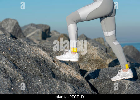 In prossimità di una donna corridori gambe in gambali in esecuzione attraverso le rocce Foto Stock