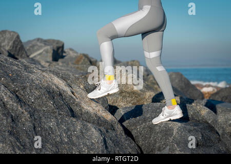 In prossimità di una donna corridori gambe in gambali in esecuzione attraverso le rocce Foto Stock