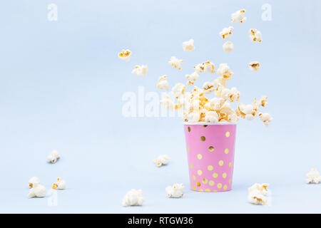 Flying Popcorn in un luminoso e di vetro su uno sfondo blu. Spazio di copia Foto Stock
