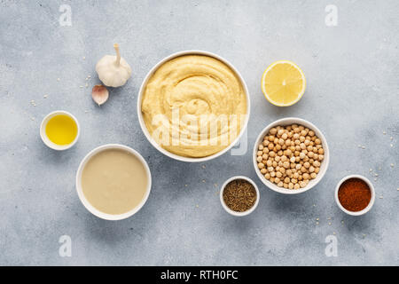 Hummus ingredienti. Ceci, tahini, olio di oliva, olio di sesamo e erbe su sfondo grigio. Set di materie prime per la produzione di humus. Cucina medio orientale Foto Stock