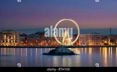 Vista notturna di illuminata ruota gigante sul lungomare di Bari, regione della Puglia, Italia. Puglia Foto Stock