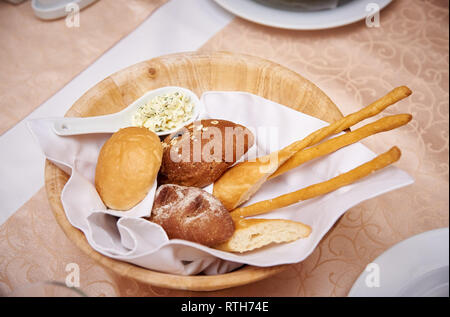 Pane fresco in una ciotola di legno su una tavola servita. Foto Stock