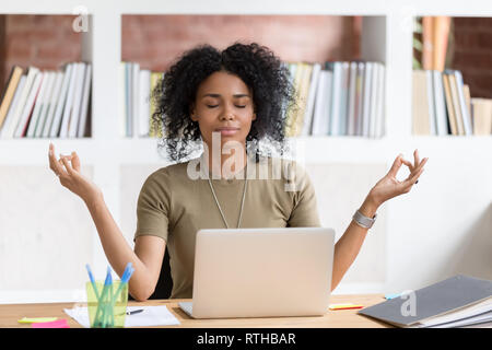 Calma imprenditrice nero facendo rompere meditando a praticare lo yoga al lavoro Foto Stock