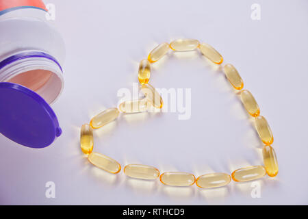 Capsule a forma di cuore ad olio di pesce. Vitamine per la promozione della salute. Concetto foto. Foto Stock
