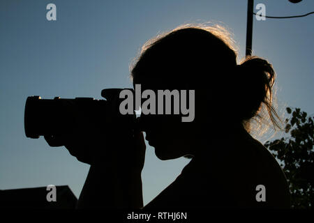 Una bellissima donna prendendo foto durante il tramonto Foto Stock