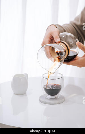 La produzione di birra nel caffè di gocciolamento. Passo per passo le istruzioni di cottura. Il caffè è pronto. Barista versando preparato del caffè in tazza Foto Stock