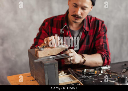 Bello artigiano utilizzando Seghetto da traforo in officina, close up foto. Lo stile di vita, occupazione Foto Stock